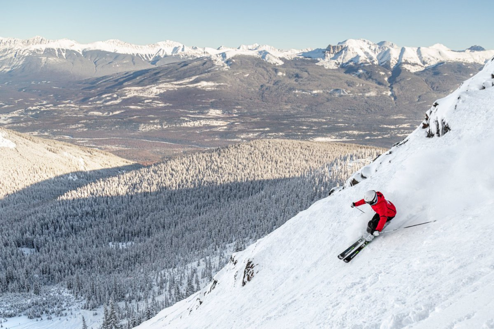 A skier goes down a mountain at Marmot Basin Ski resort with views of the Canadian Rockies in the background